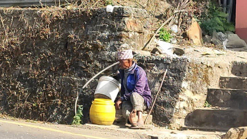 An elderly man waits for his turn at the rotational water supply tap in Sindhupalchok