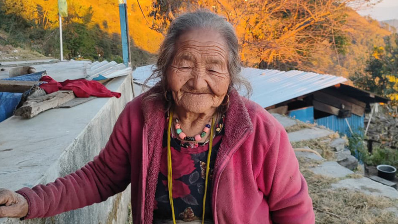 A grandmother cares for grandchildren while managing agricultural tasks in Sindhupalchok